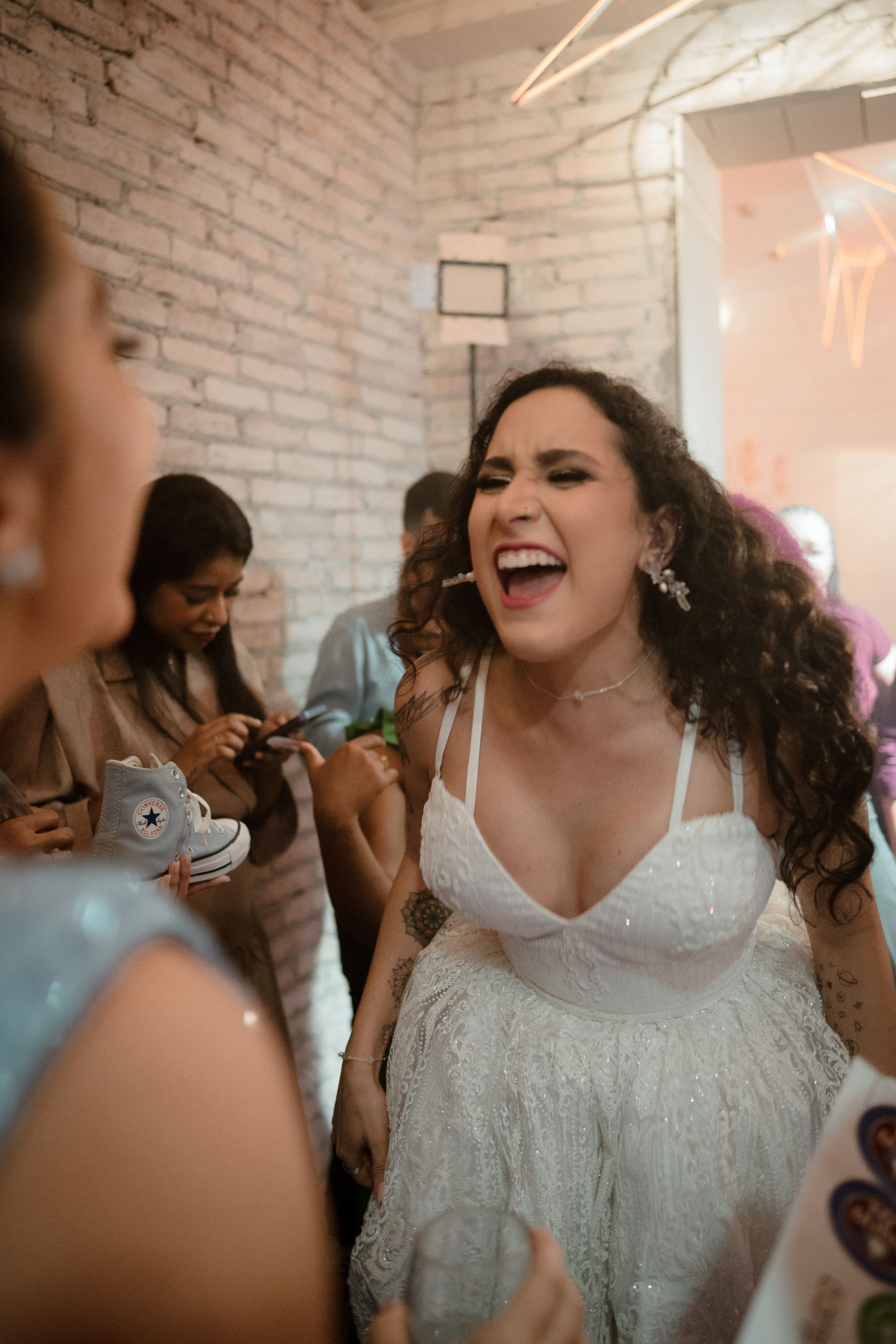 Wedding reception dance floor moments captured with white brick walls and festive lighting.