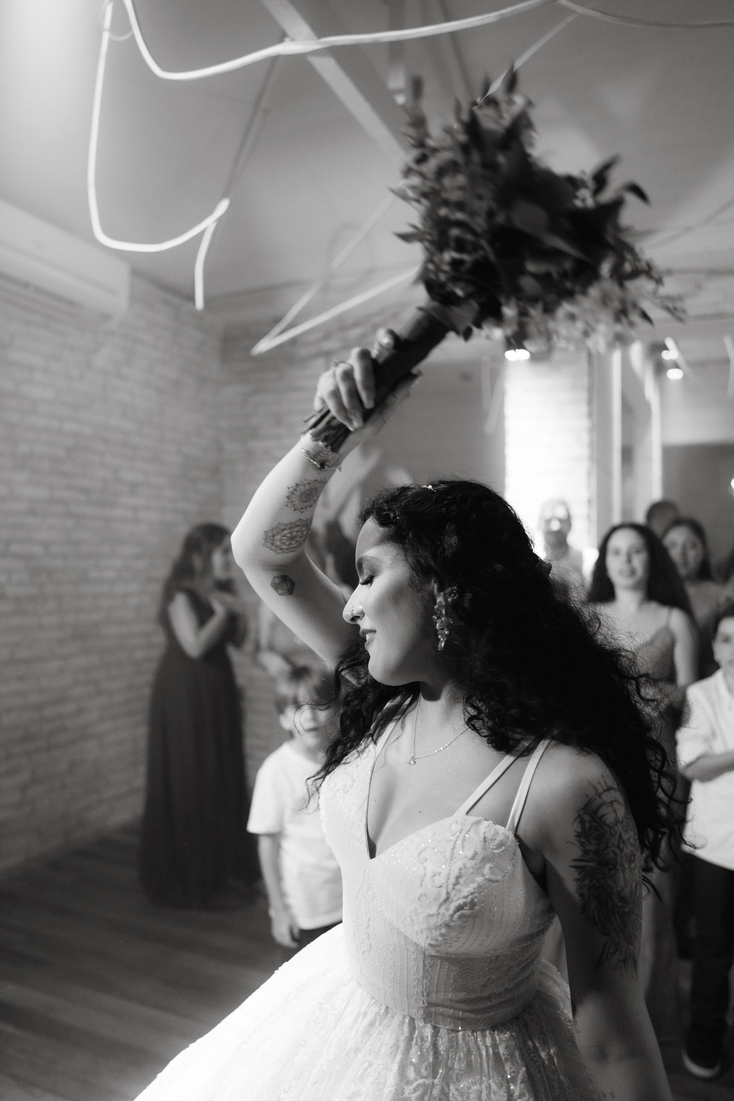 Black and white photo showing energetic dancing at a wedding reception with flowing white dresses.