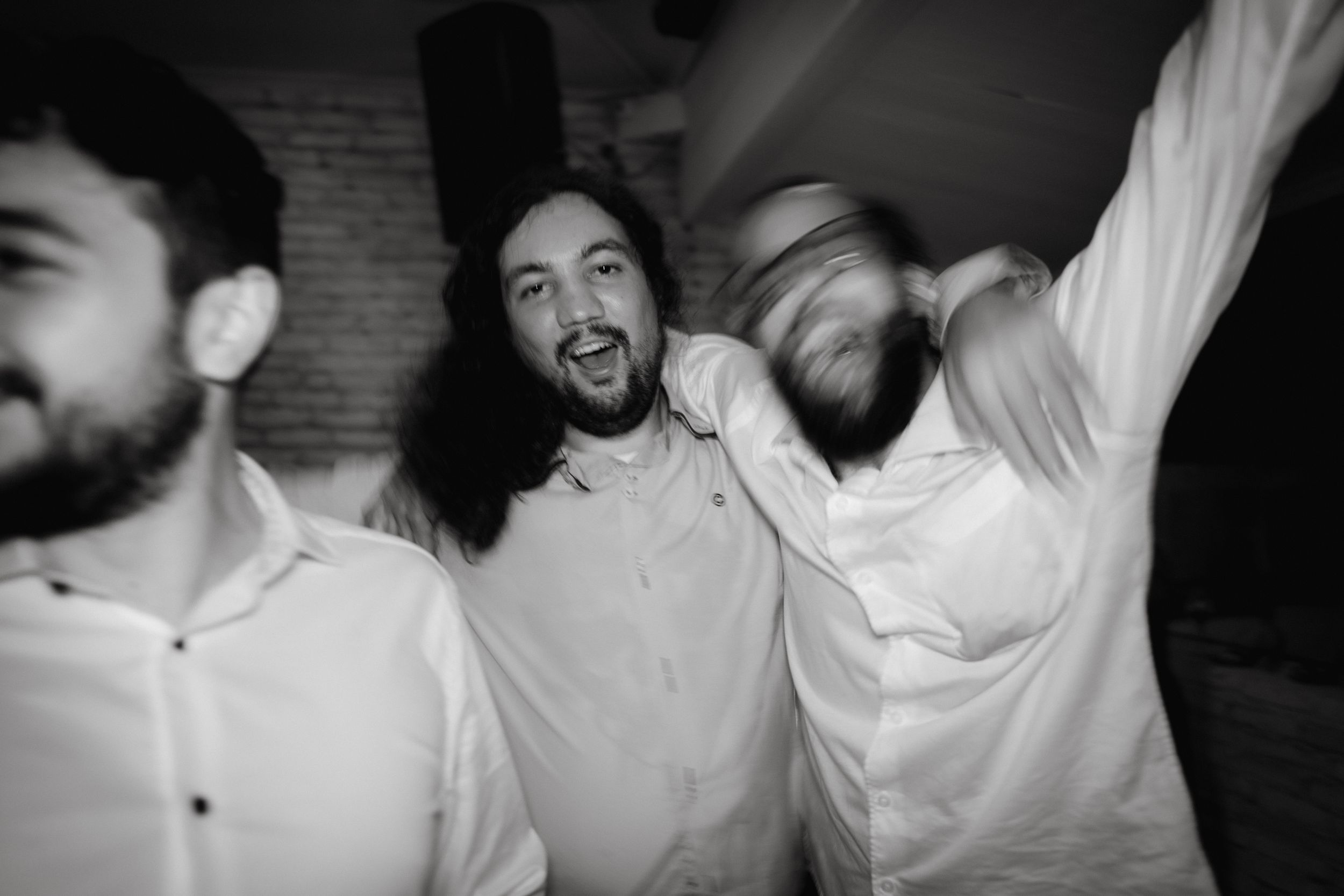 Black and white photo of three friends dancing and celebrating at a party.