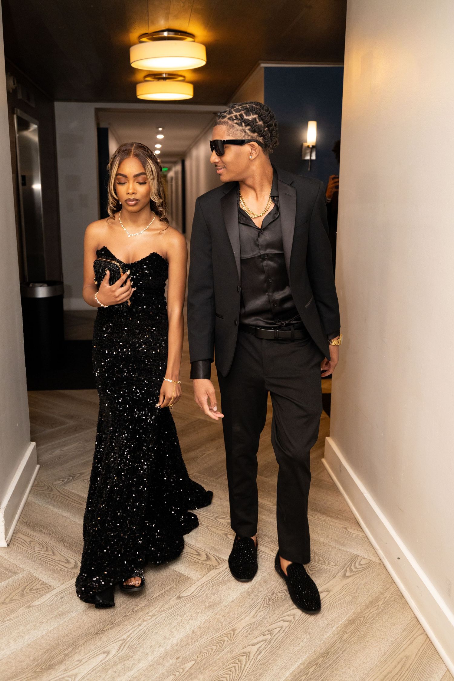 Elegant couple walking in hallway wearing black formal attire.