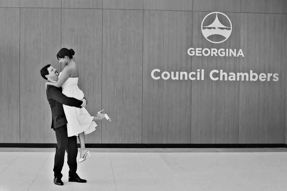 Couple sharing a romantic lift embrace in black and white photo outside Georgina Council Chambers.