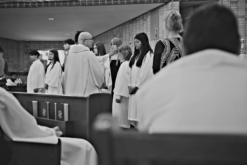 Black and white photo of a church congregation with robed clergy and choir members standing during a religious ceremony.
