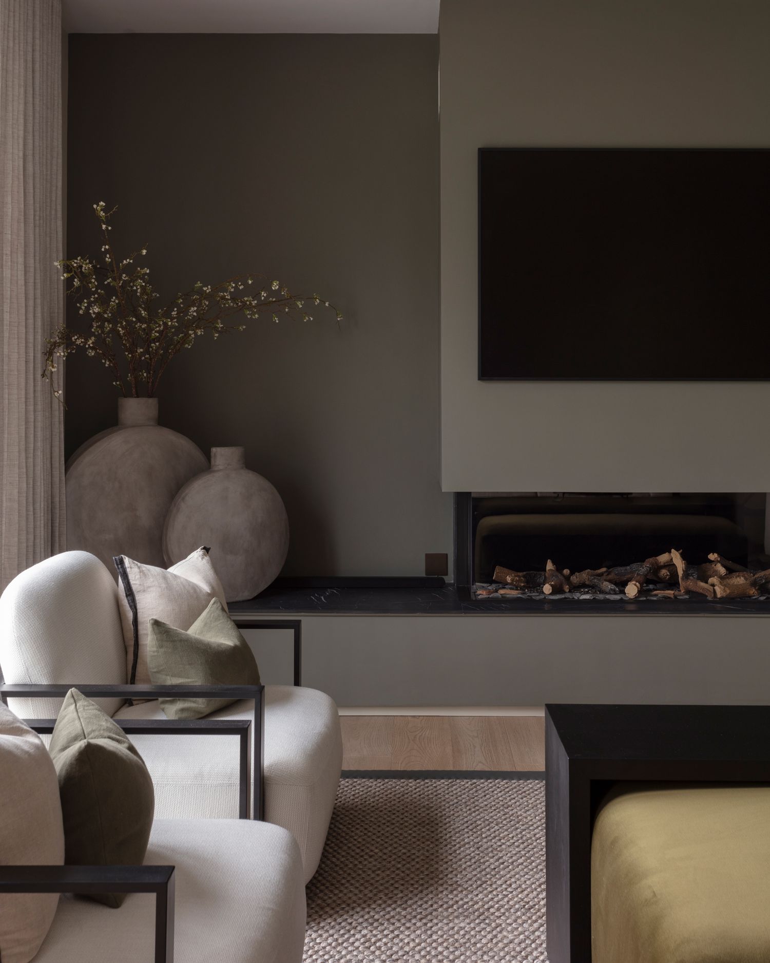 A modern living room interior with grey walls, built-in shelving, and contemporary furnishings in neutral tones.