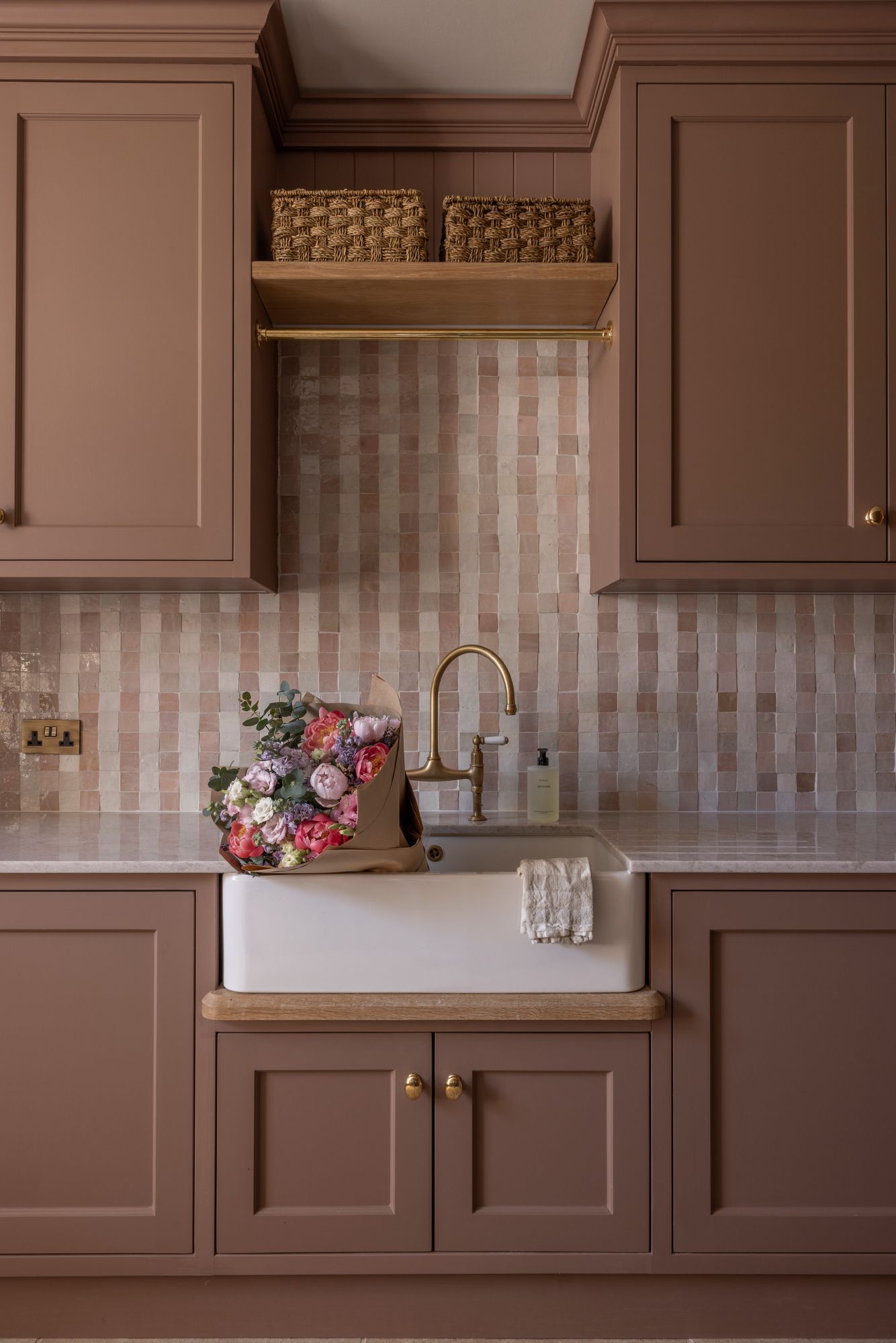 Modern kitchen with brown cabinets, geometric backsplash, and pink floral decorative accents on the counter.