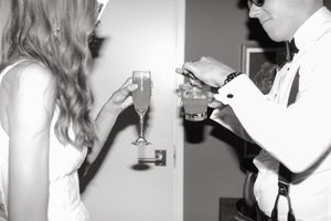 A black and white photo shows two people with champagne glasses in what appears to be a celebration setting.