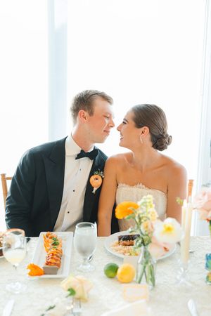 A wedding couple sharing an intimate moment at an elegant reception table with citrus decor at the Dallas Arboretum's a Tasteful Place.