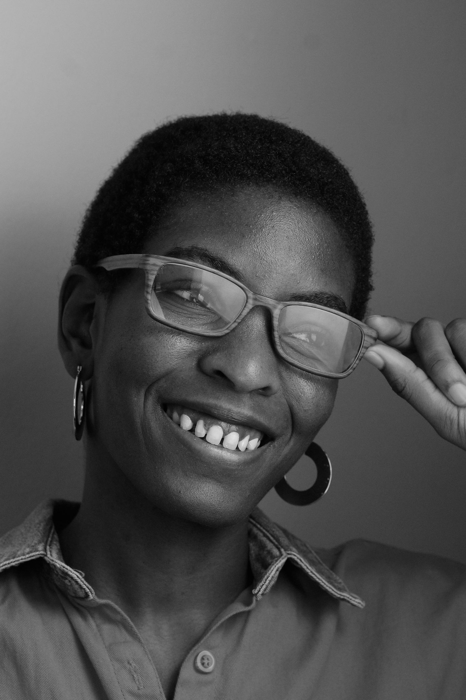 Professional headshot of a person in glasses with a bright genuine smile in black and white.