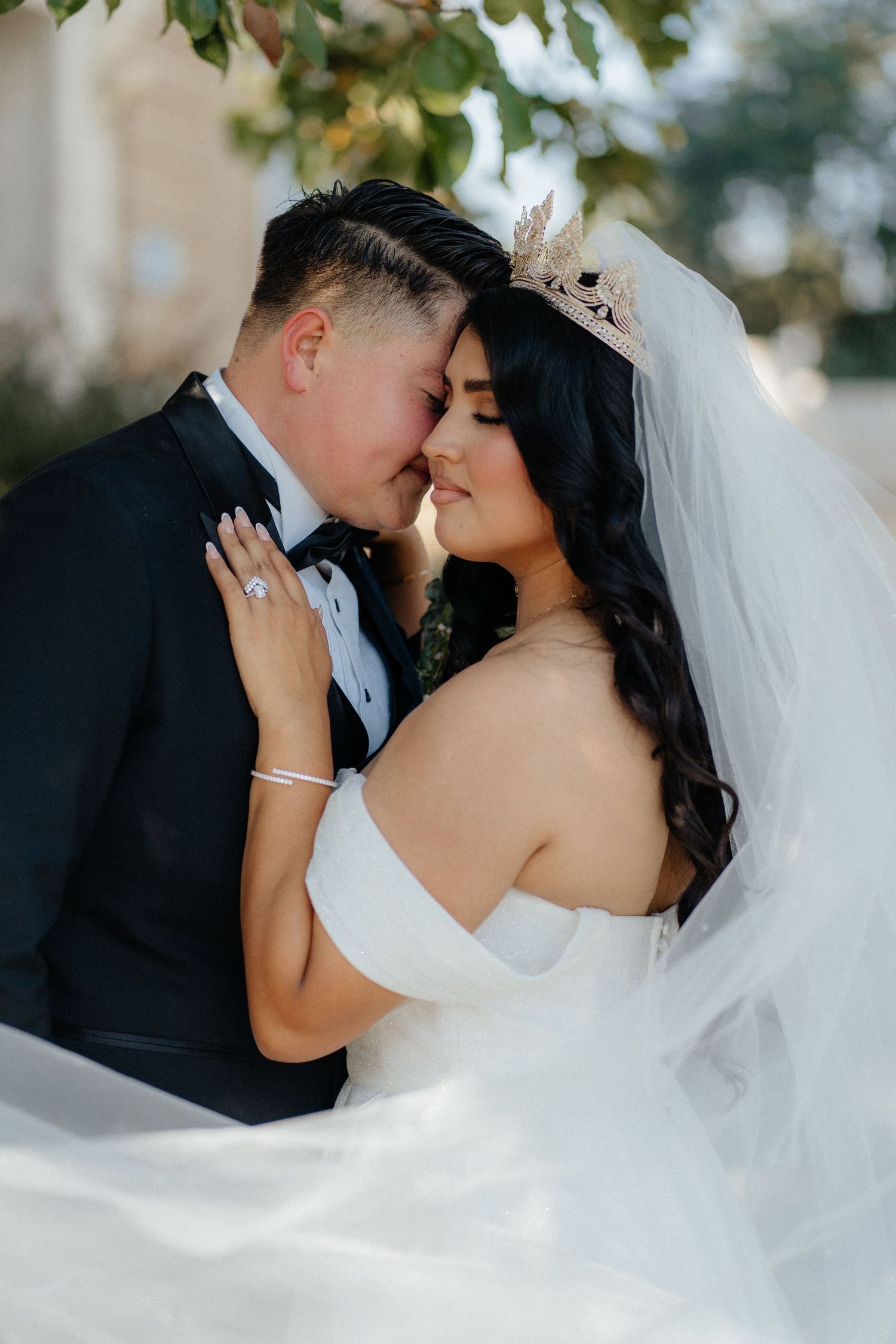 Intimate wedding portrait of couple sharing a romantic moment against a white backdrop with soft lighting.
