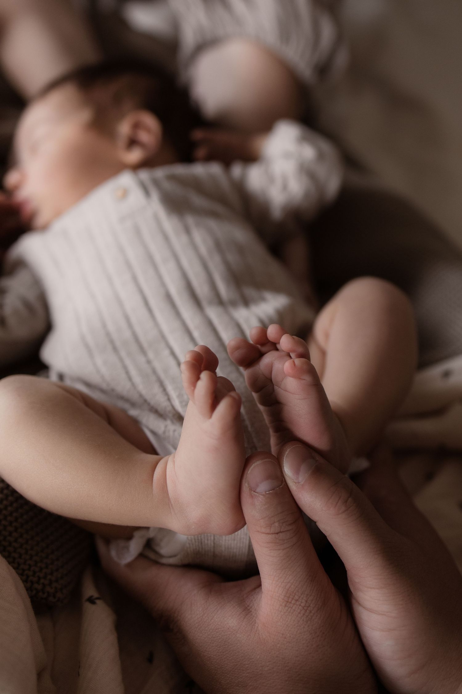 Newborn shoot thuis met baby slapend op bed.