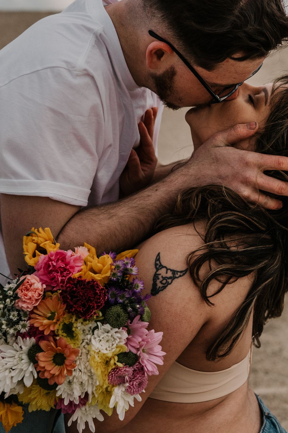Intimate romantic moment with colorful wildflower bouquet featuring sunflowers, daisies and pink blooms.