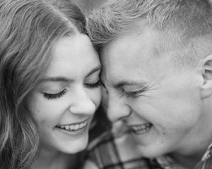 Black and white close-up portrait of a smiling couple touching foreheads in a romantic and tender moment.