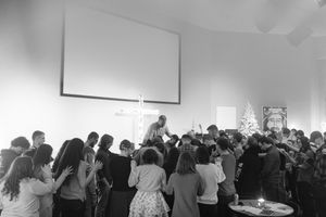 Large congregation gathered in prayer around altar in modern church.