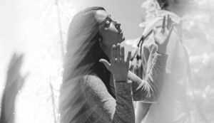 Black and white photo of a woman with long hair reaching out toward another person in a dreamy, artistic scene.