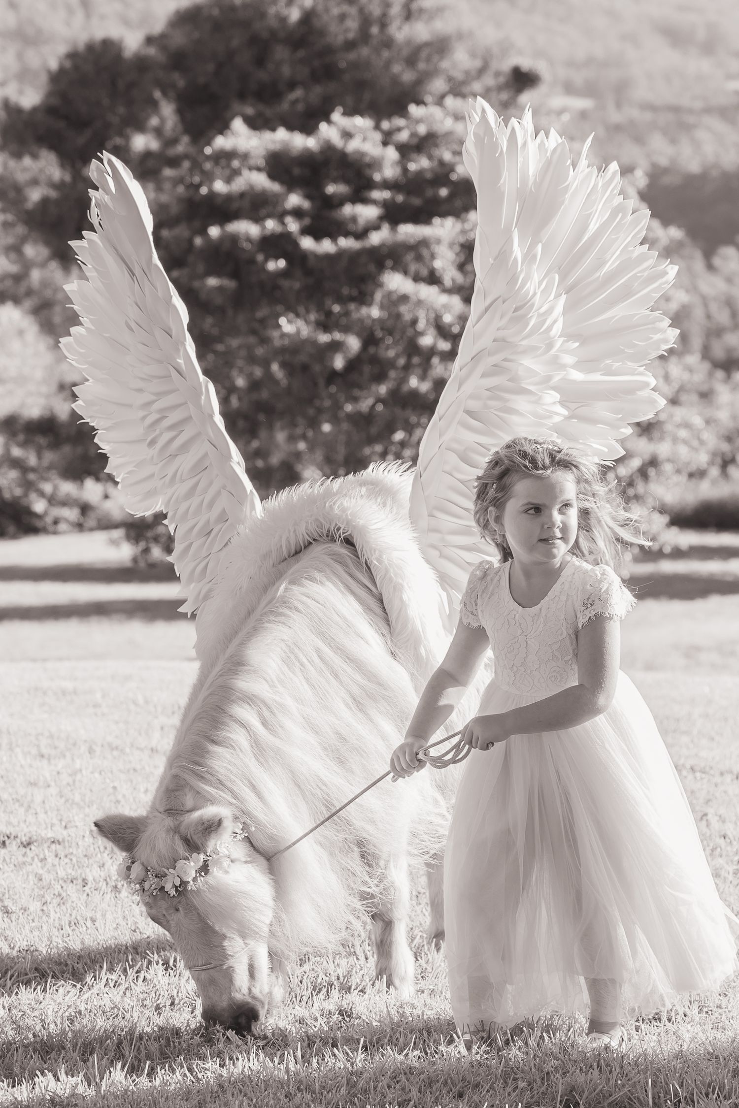 Ethereal black and white photo featuring white angel wings and flowing dress in motion.