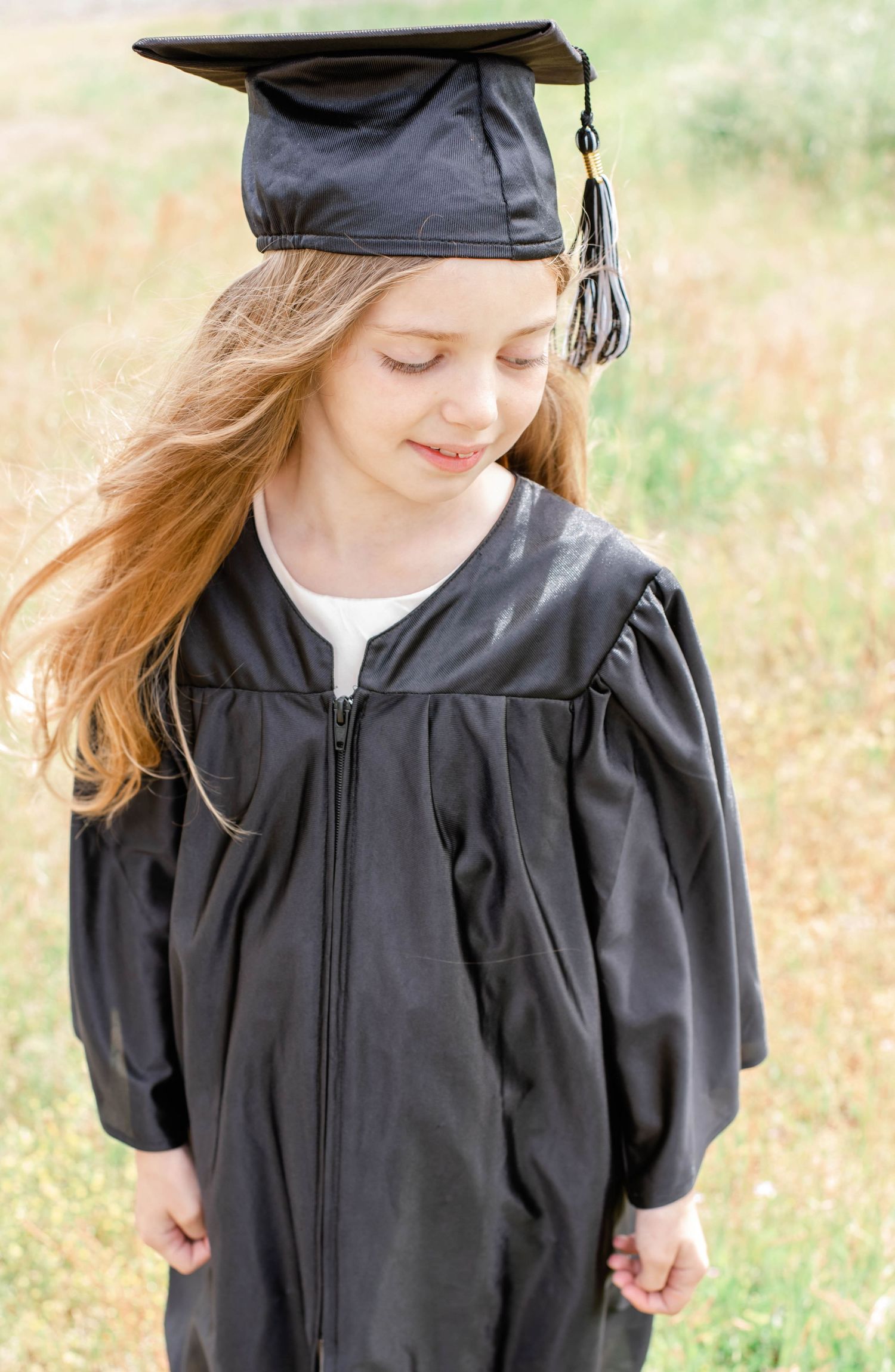 Close-up of graduation gown details and tassel against natural outdoor setting.
