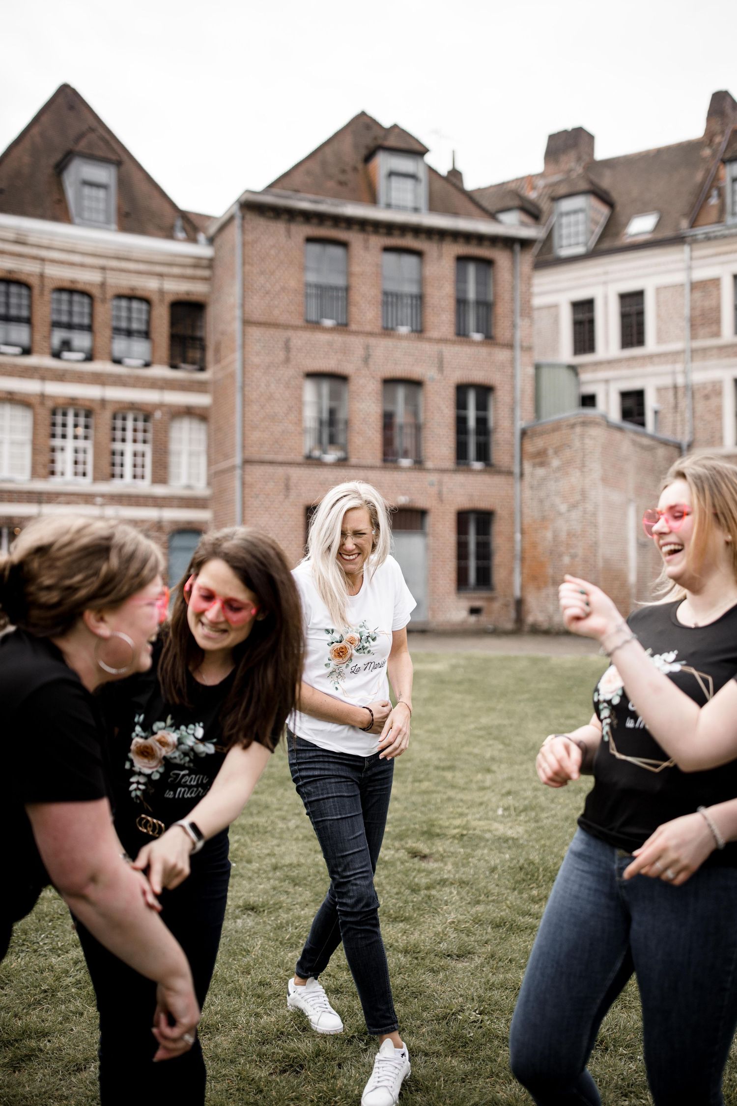 Friends sharing laughter and joy while hanging out on a lawn in front of vintage architecture.