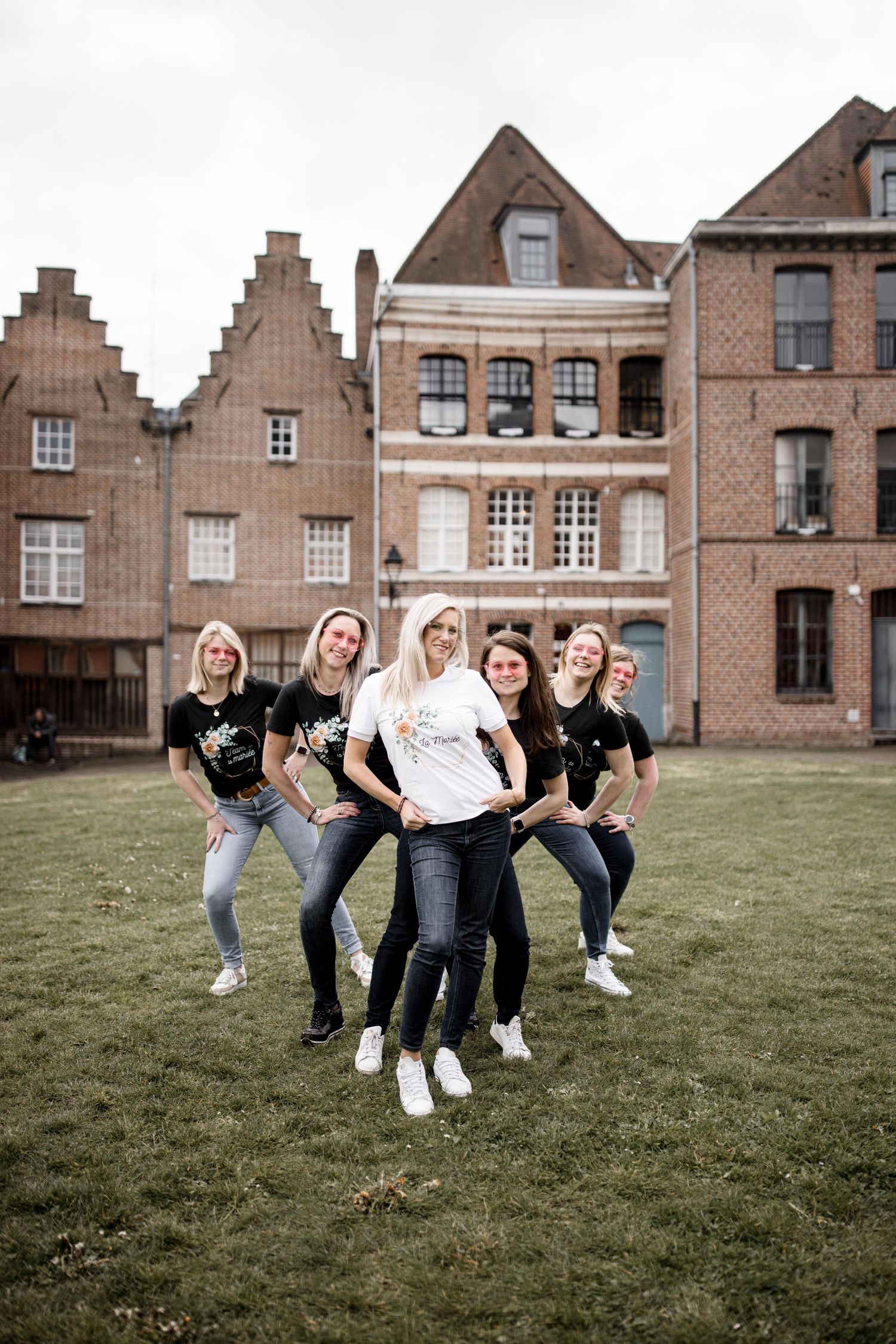 People posing playfully in matching outfits against classic European architecture.