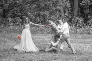 Candid black and white wedding photo capturing fun moment between wedding party members.