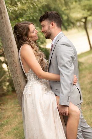 Intimate wedding couple portrait against rustic tree backdrop in natural lighting.