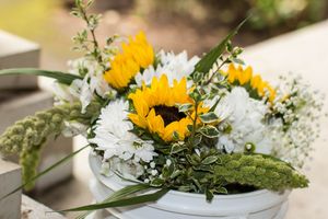 White bowl arrangement with sunflowers, white mums, greenery, and baby's breath centerpiece.