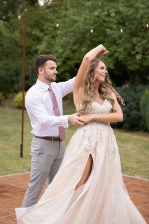 A couple dancing together on a wooden deck with string lights in the background.