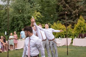 Celebration at an outdoor wedding reception as guests cheer and dance on the lawn.