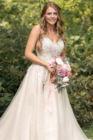 Romantic garden wedding portrait featuring a flowing tulle gown and pink floral bouquet.