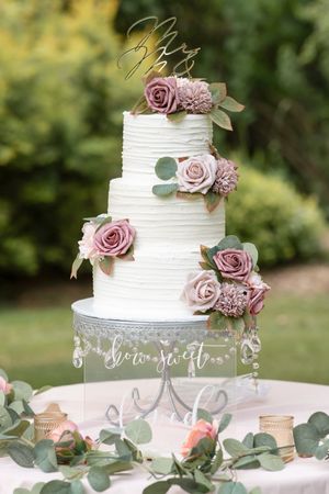 White wedding cake with edible flower decor.