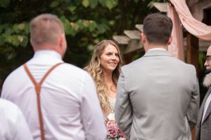 Wedding ceremony candid shot with guests and decorative pink fabric draping overhead.
