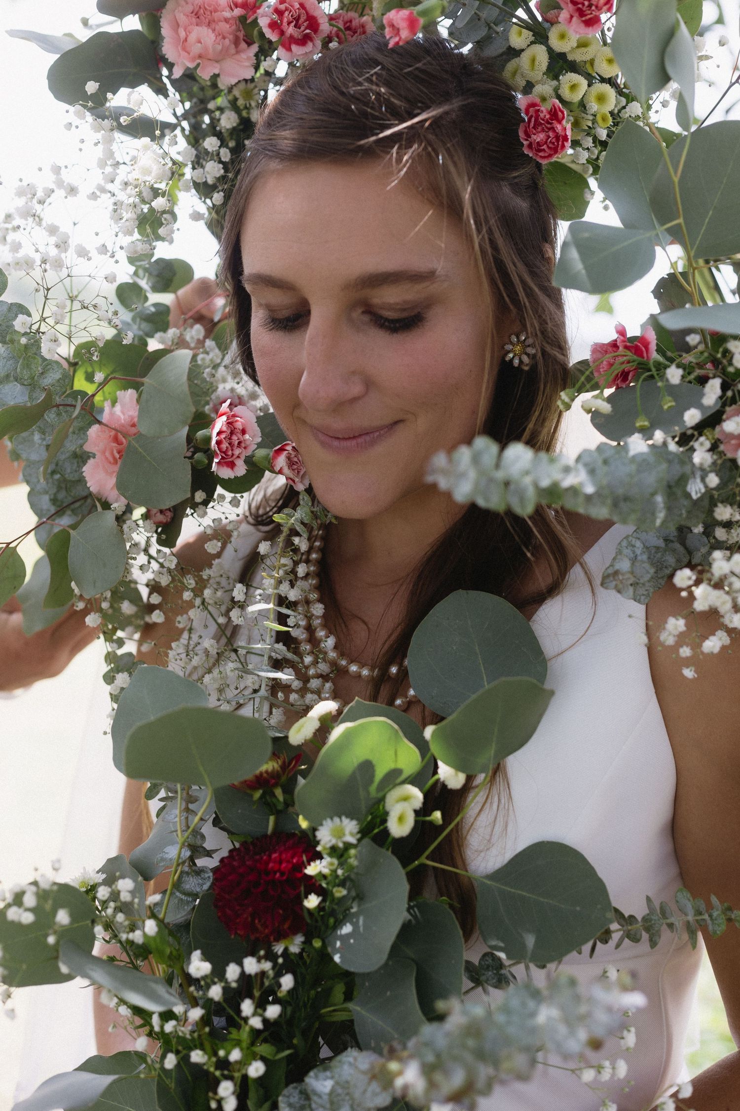 A delicate white wedding dress hangs against dark wooden columns in a classic interior setting.