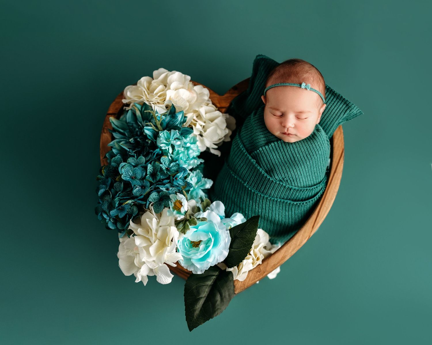 Newborn photography setup with teal backdrop and delicate floral arrangements. Middle TN newborn Photographer.