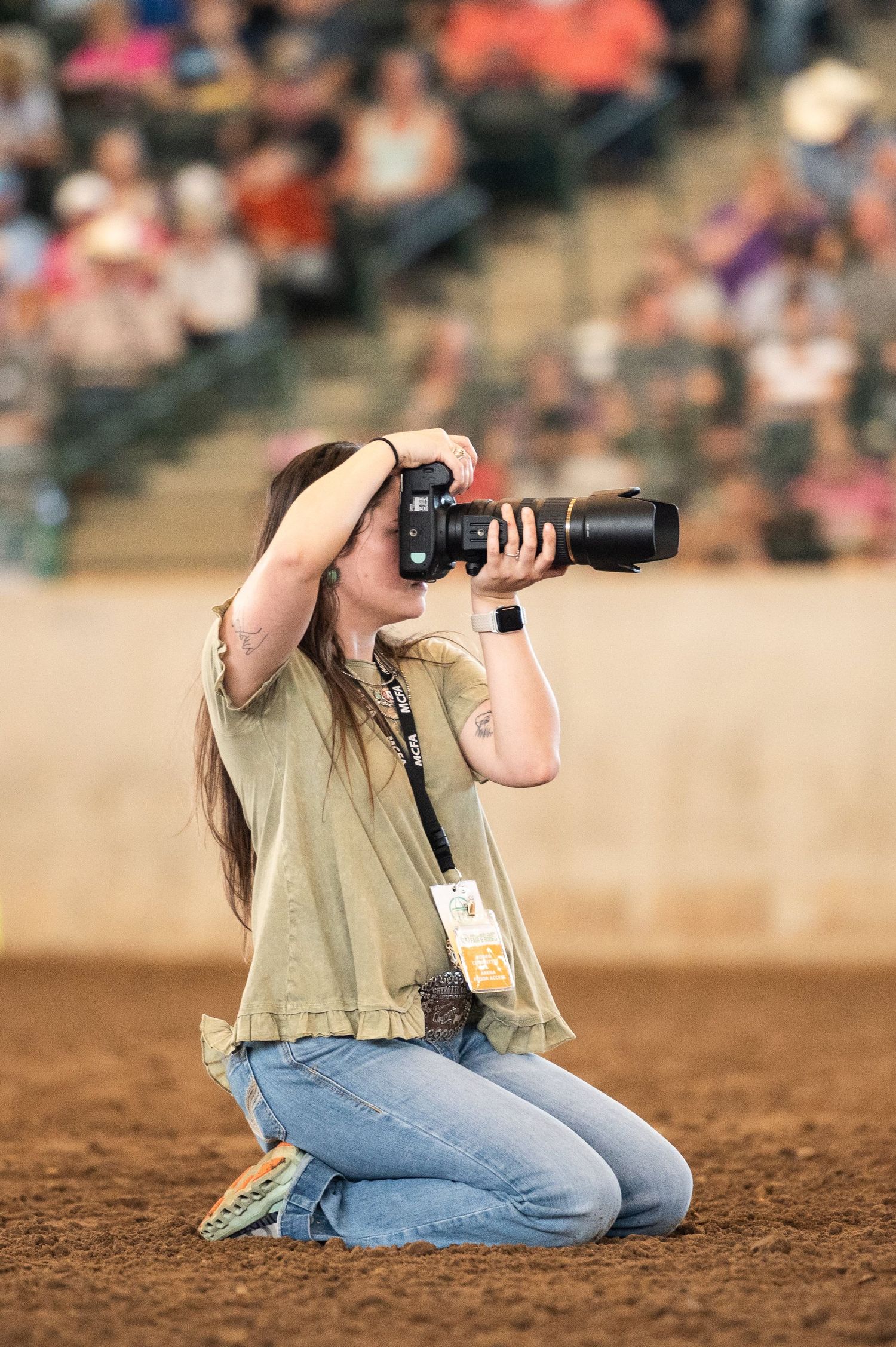Photographer lying on dirt ground with professional camera capturing low angle shots.