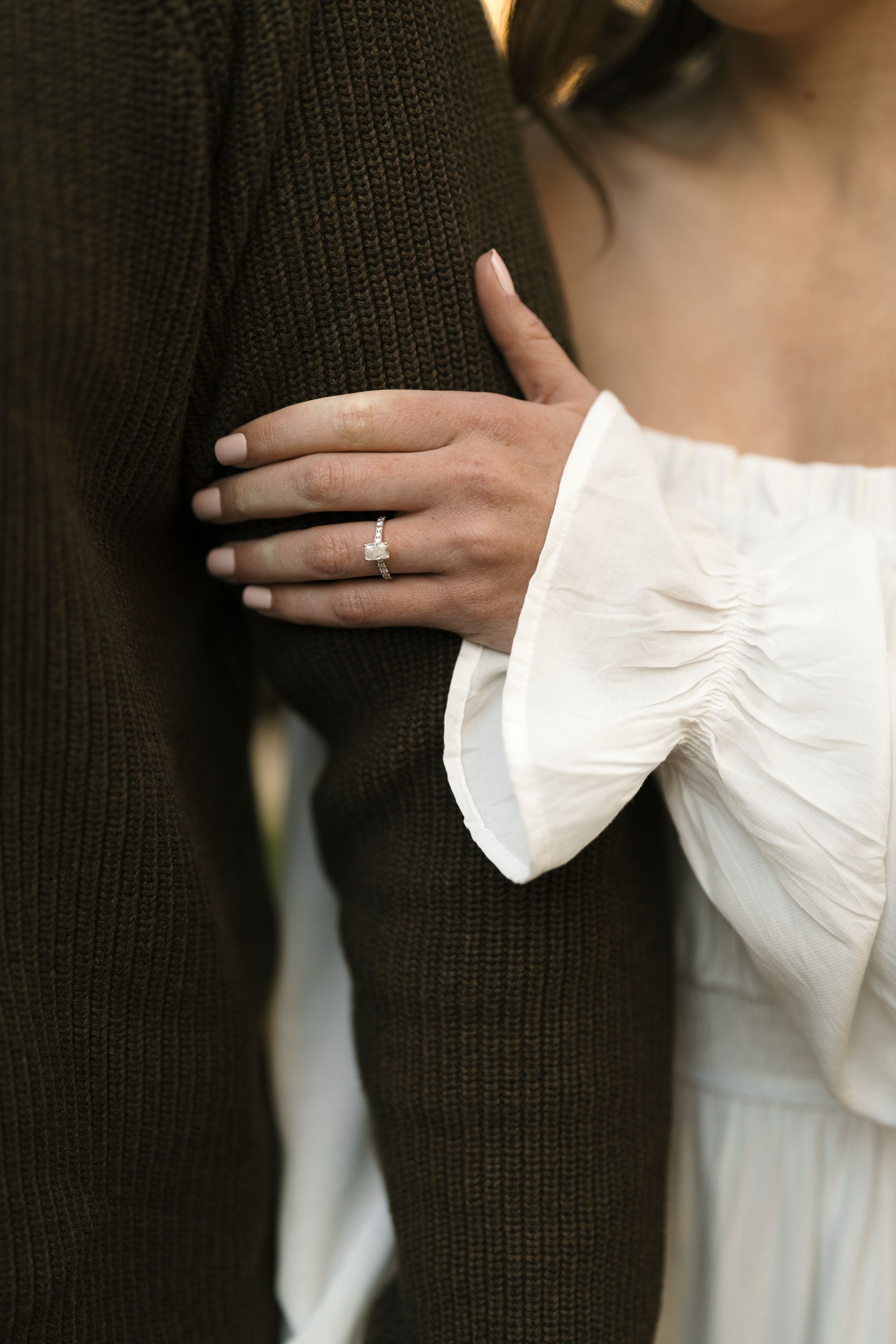 Close-up series of hands showing engagement ring on finger against dark and light contrasting clothing.