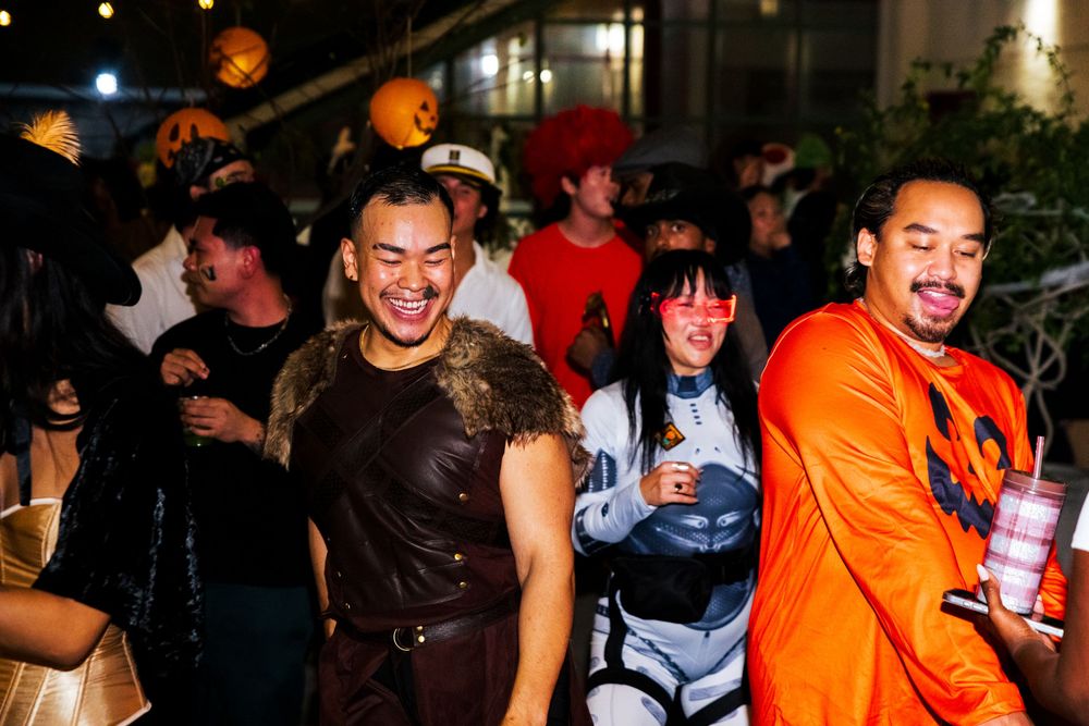 Group of people dancing and socializing at a lively nighttime party with orange and dark lighting.