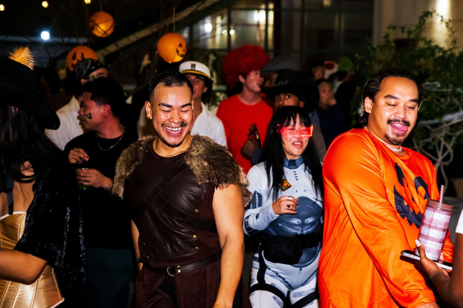Group of people dancing and socializing at a lively nighttime party with orange and dark lighting.