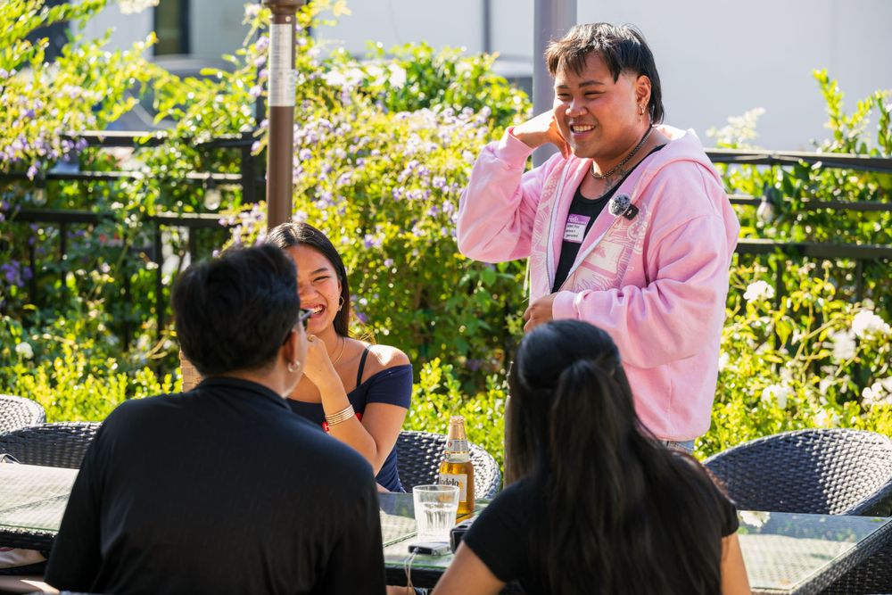 Group of friends enjoying drinks and conversation at an outdoor patio table.