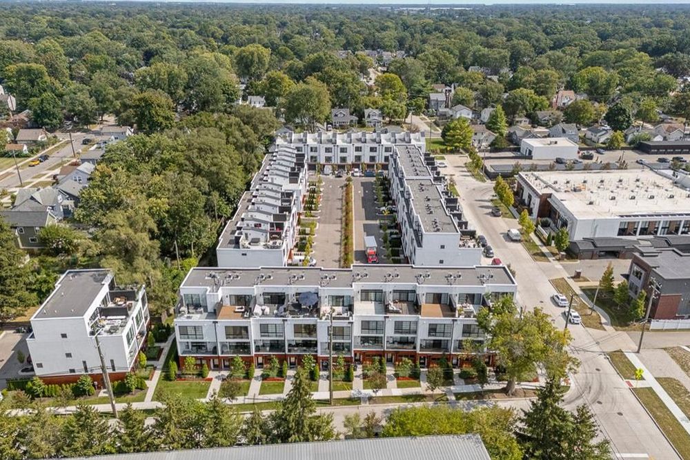 Aerial view of modern townhouse complex surrounded by mature trees in a suburban neighborhood.