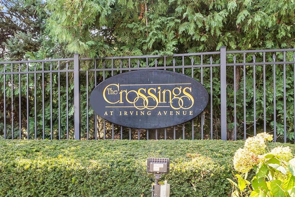 Elegant entrance sign for The Crossings at Irving Avenue surrounded by lush greenery.