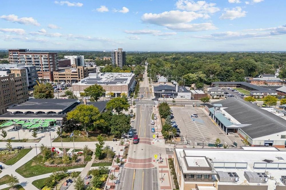 Aerial view of a vibrant downtown corridor with tree-lined streets, shops, and city buildings.