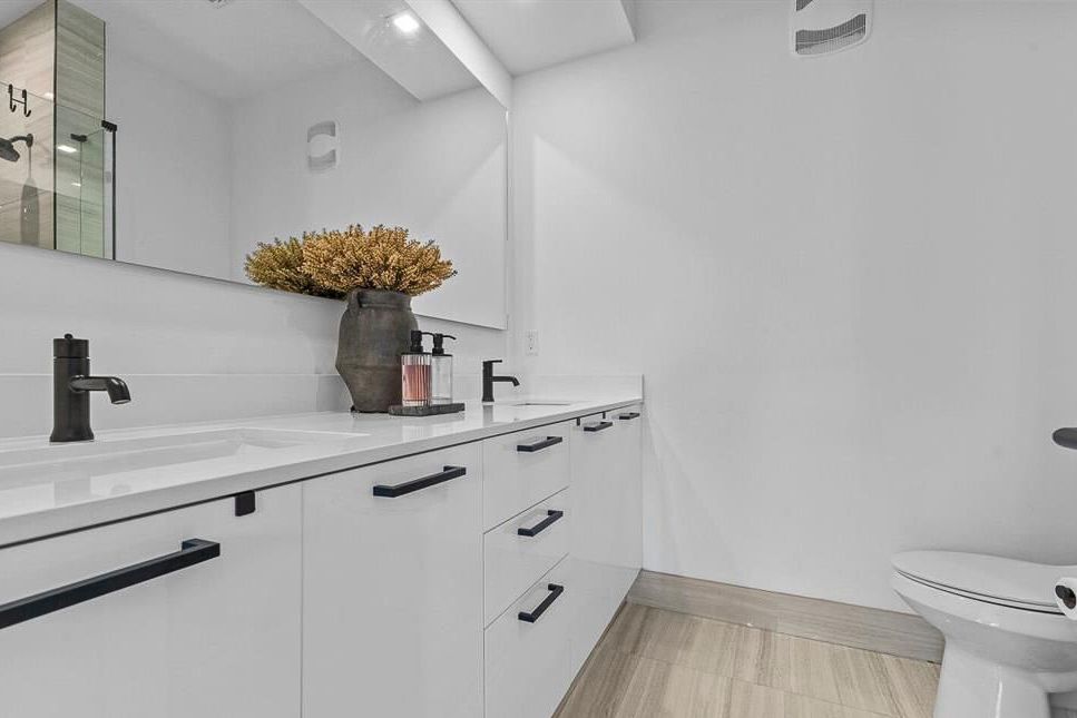 Sleek white bathroom vanity with double sinks, black hardware, and quartz countertop.