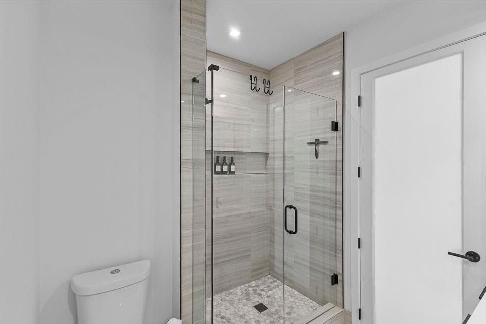 Contemporary bathroom with glass-enclosed walk-in shower, tile walls, and mosaic floor.