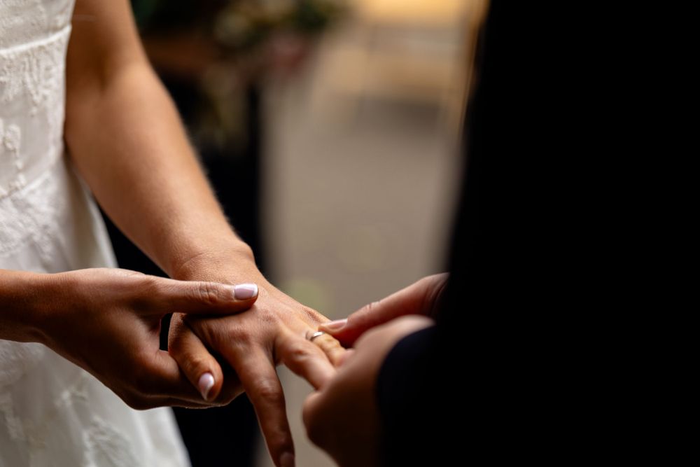 Intimate close-up of hands exchanging rings during wedding ceremony.