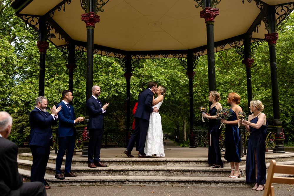 Wedding ceremony in a garden gazebo with wedding party lined up on both sides.