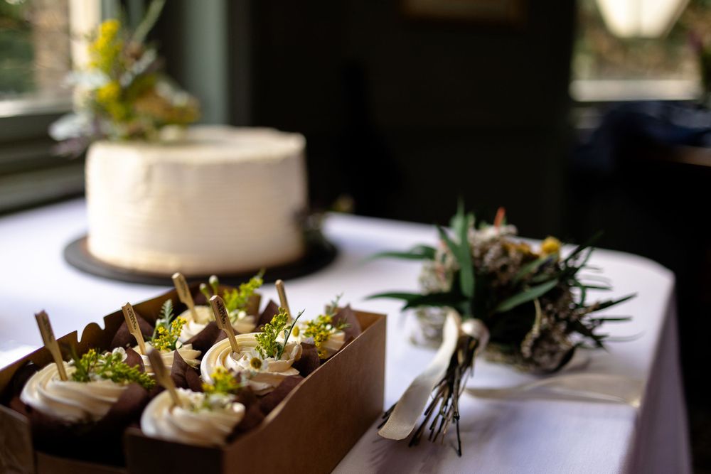 Wedding reception details with white cake and appetizers on wooden serving tray.