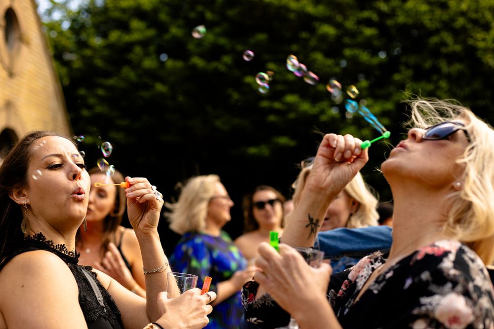 Group of people joyfully blowing bubbles together at an outdoor gathering.