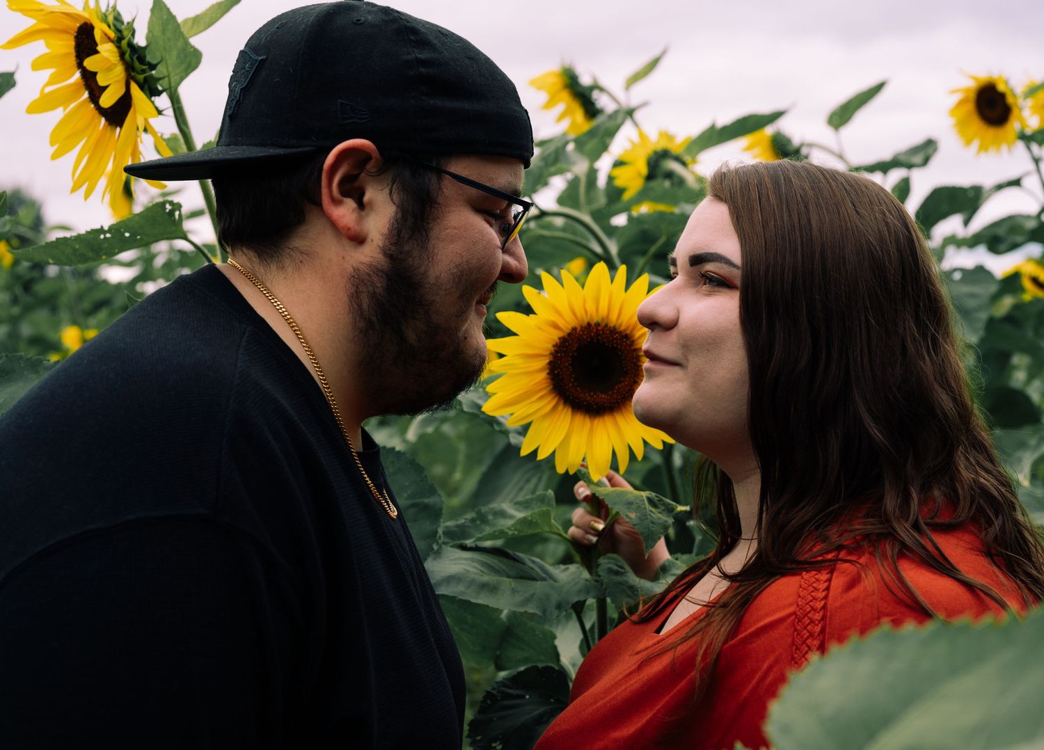 A romantic couple sharing intimate moments in a sunflower field during sunset.