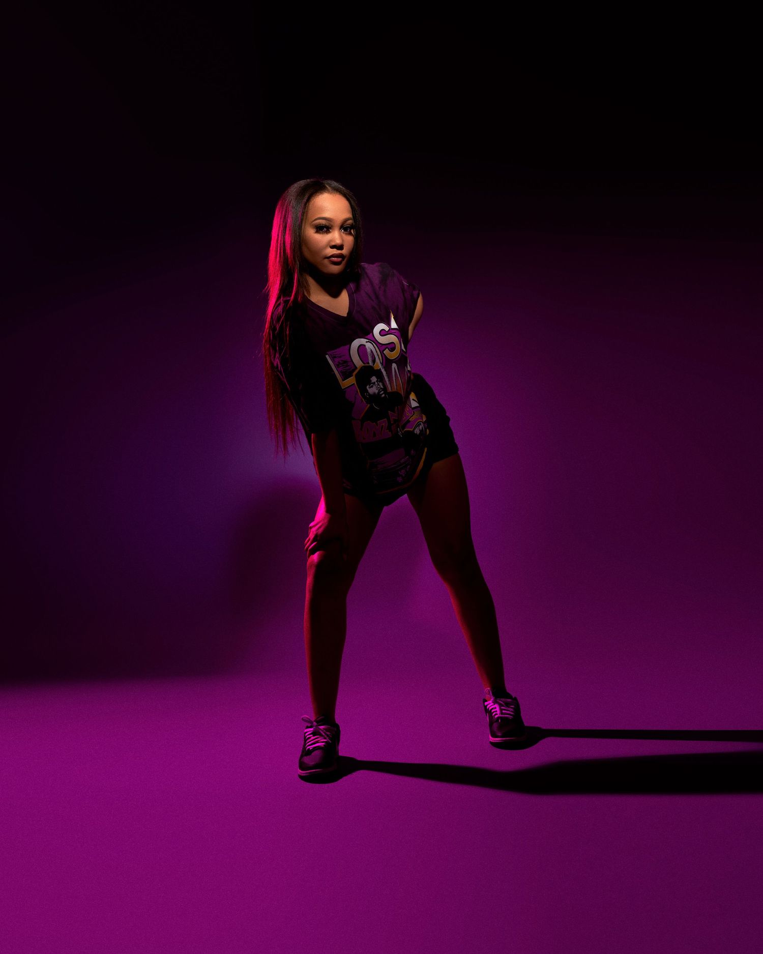 Dancer strikes dynamic pose in black activewear against purple backdrop.