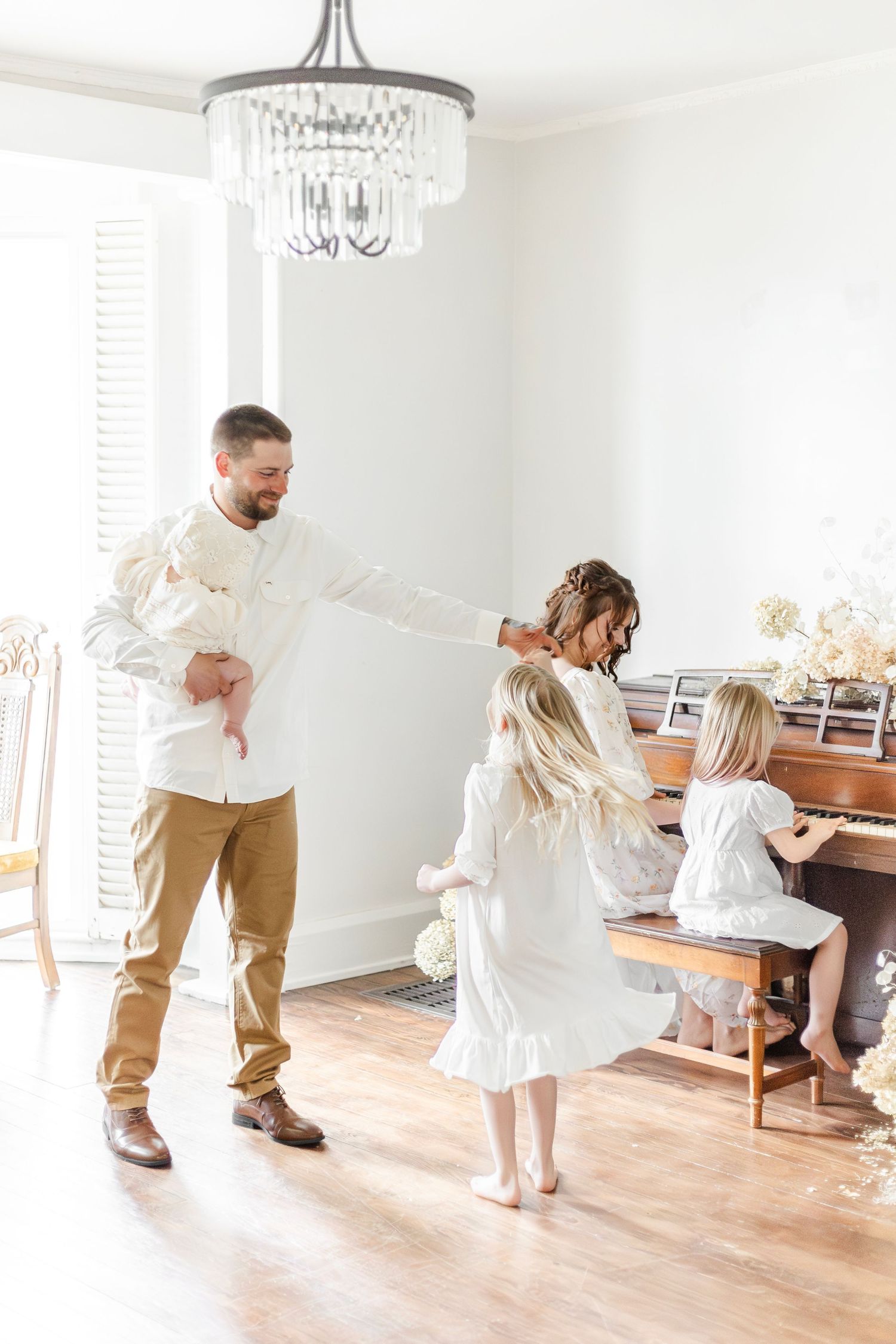 Family dancing together in living room while mom plays the piano.