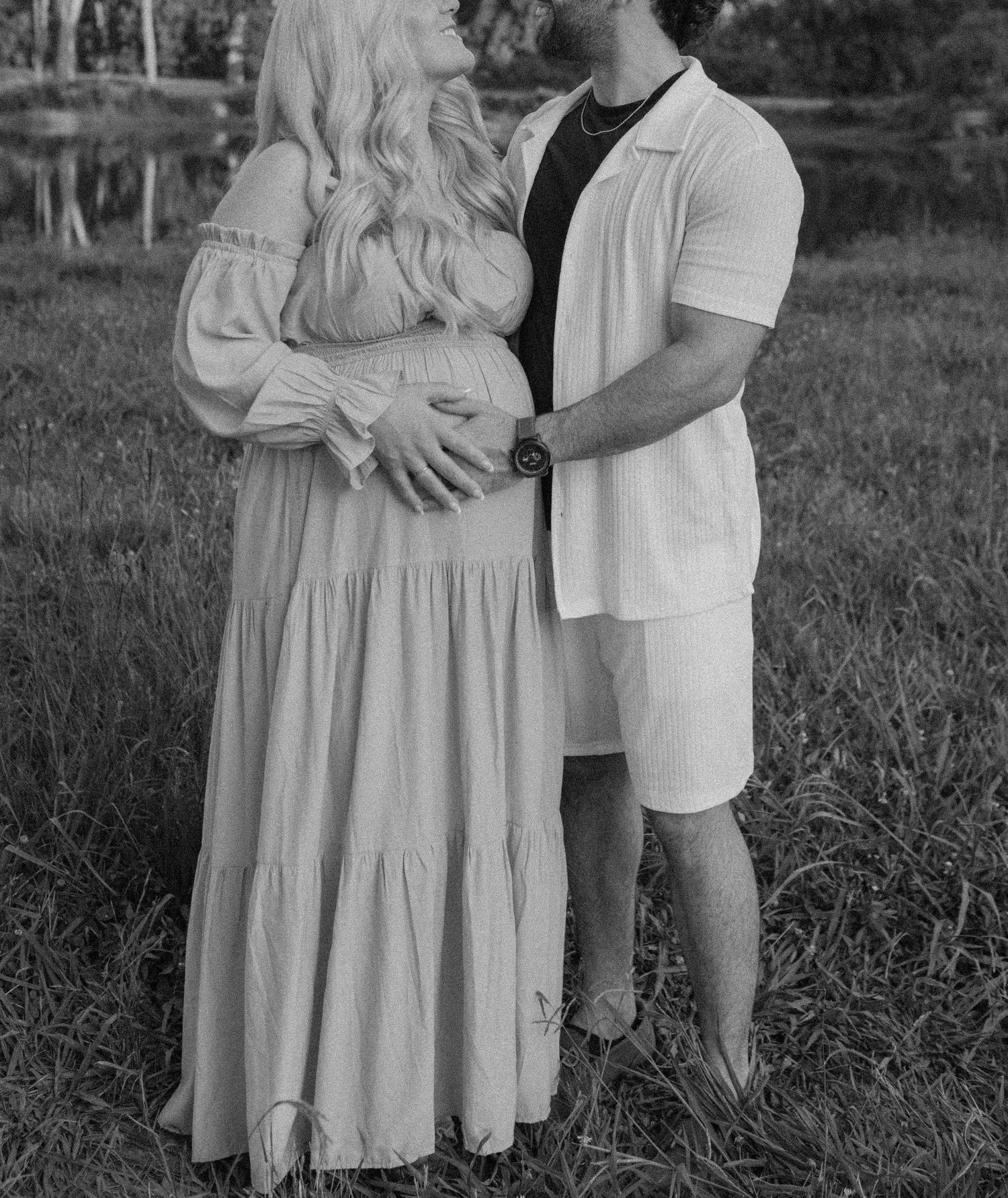 Black and white photo of couple embracing in flowing dress and casual wear outdoors.