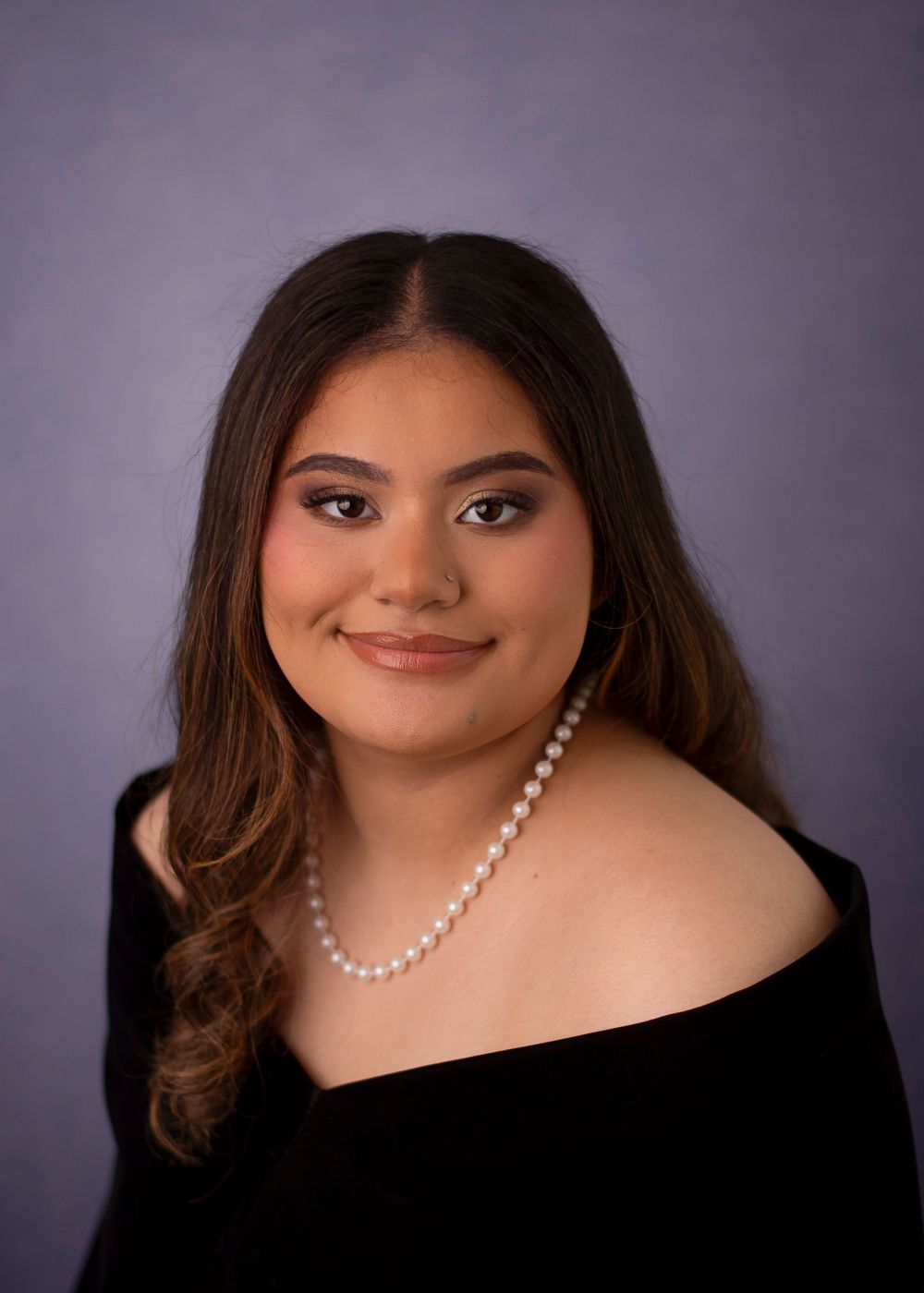 Formal portrait of a young woman in an off-shoulder black dress with pearl necklace.